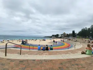 Coogee Beach and foreshore viewed from the Bondi to Coogee Coastal Walk, featuring the colourful rainbow promenade, sandy beach and relaxed coastal atmosphere.