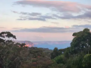 A peaceful Blue Mountains landscape near Katoomba, featuring rolling forested valleys, sandstone escarpments and soft pastel skies stretching across one of Australia's most iconic natural regions.